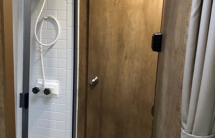 In mid-section, shower is on curb side of camper. In this picture, the bathroom door  is all the way open, spliting bedroom and bathroom areas off  from back of camper for privacy