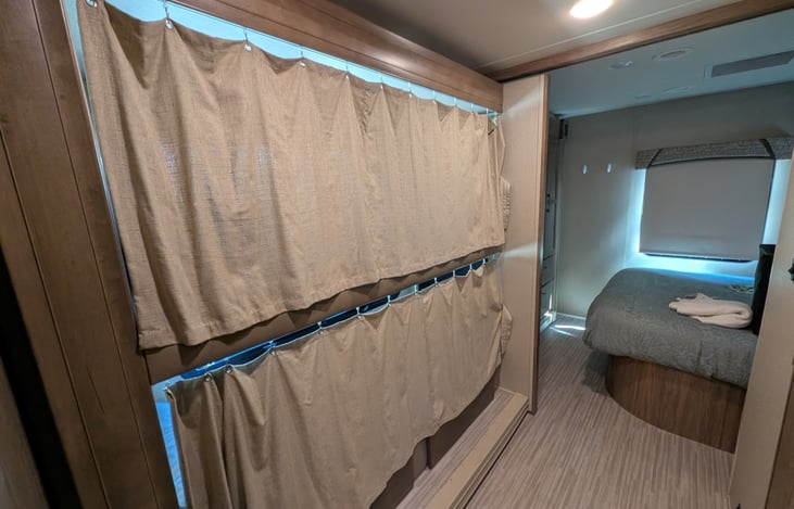 Spacious hallway with bunk beds (each with privacy curtains) leads to a cozy private bedroom with a queen-sized bed. Perfect for little nappers or teens who want to sleep late!