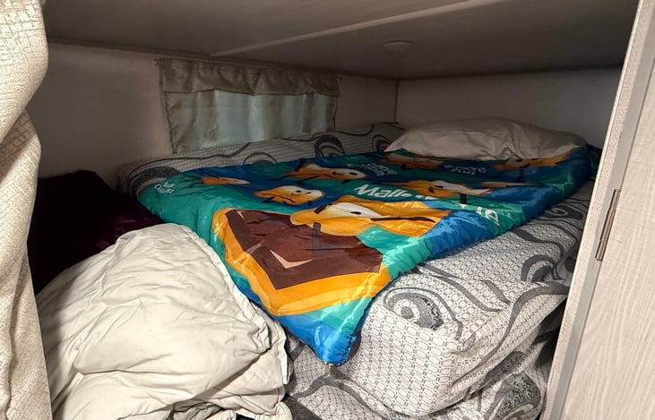 Top bunk bed with pillow, kids sleeping bad, double mattress pad and extra blankets.