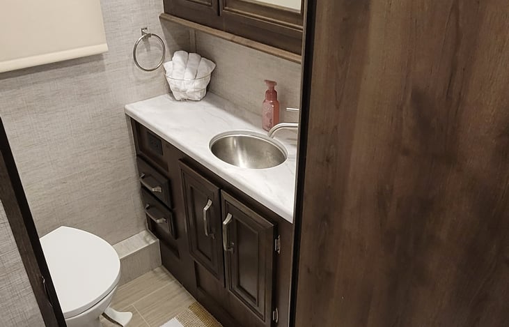 Bathroom with door, sink and medicine cabinet overhead ventilation