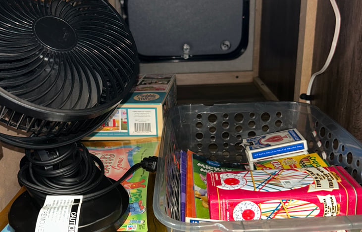 Personal desk fan, magazines, games and activities under front dinette storage. Storage is also accessible from outside.
