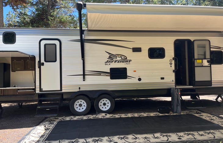 Exterior with 2 entrances. 1 to bathroom and 1 to kitchen. Outdoor kitchen with fridge, sink, and 2 burners. Outdoor rug also included.
