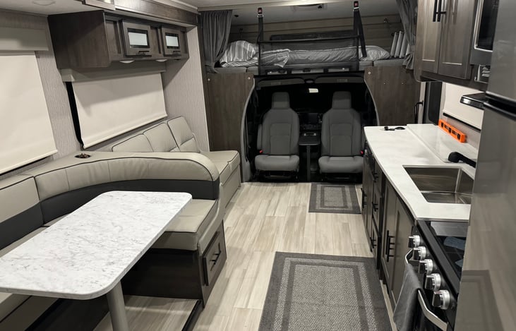 Main living space with U shaped dinette and couch. Captain chairs swivel to make additional seating in the living space.