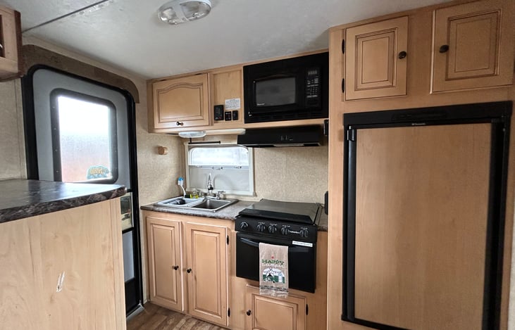 Full kitchenette with Refrigerator and small inner freezer, Microwave, Oven, Stovetop, and double kitchen sink with pull down sprayer.