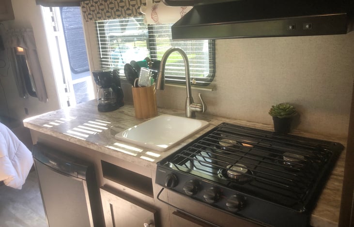 View from the bunk beds.  Kitchen with overhead storage, microwave, 3-burner stove top.  Kitchen comes fully equipped.  See RV details for list.  Entrance/exit door to left of kitchen counter