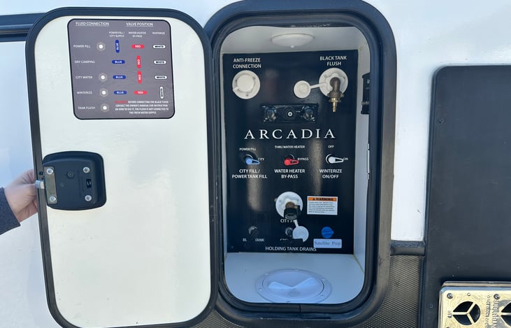 Exterior utility control panel with city water connection, black tank flush, water heater bypass, and winterization valves.