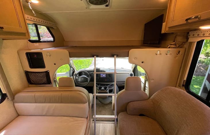 Overhead bunk bed is equipped with large TV that swivels to face dining/living area!