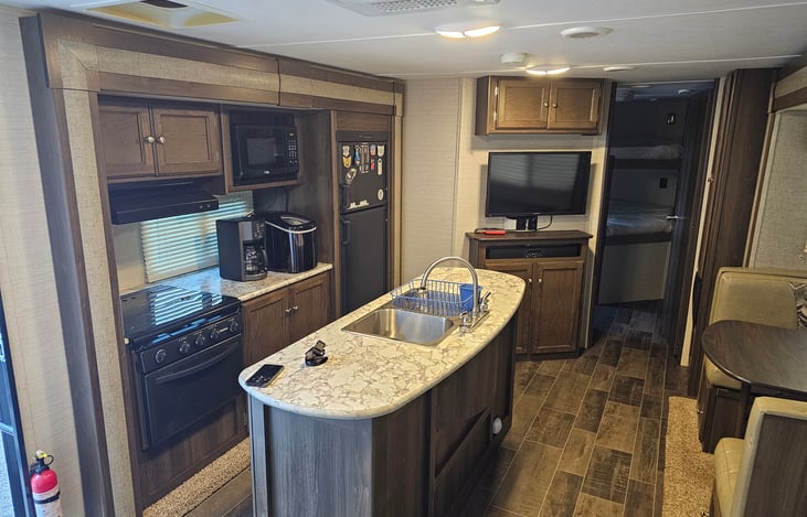 Extra large living area with two slide-outs and an island sink. TV with Roku device. Indoor and outdoor Bluetooth soundbar. Fold out couch and convertible sleeper dinette.
