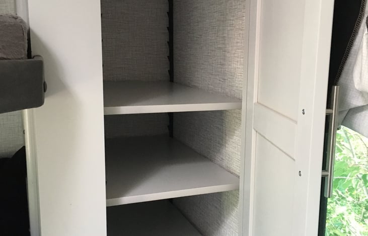 The bunk room features hanging storage and shelving and offers plenty of space for all your camping necessities.