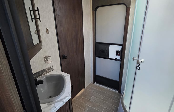Sink and shower in full bathroom with exterior door and door to master bedroom.