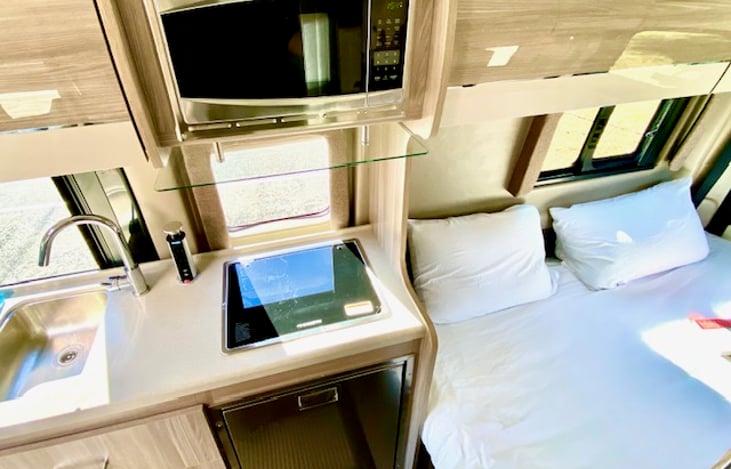 Fully equipped kitchen includes propane powered stovetop, microwave, sink, fridge, freezer, utensils, plates, coffee maker, and coffee!