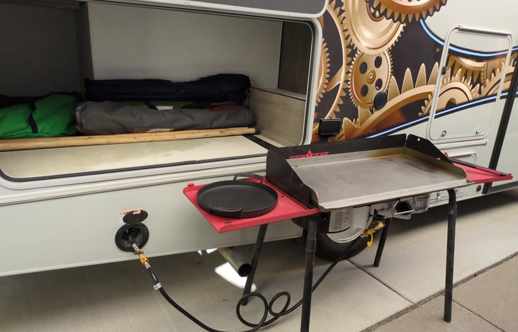 Camp chief w/grill, hooks up to the RV. No need to bring extra propane tanks. Cooking out side keeps the RV cool & able to cook for big groups. 2 hiking sticks. 4 camp chairs, & Space for your gear.