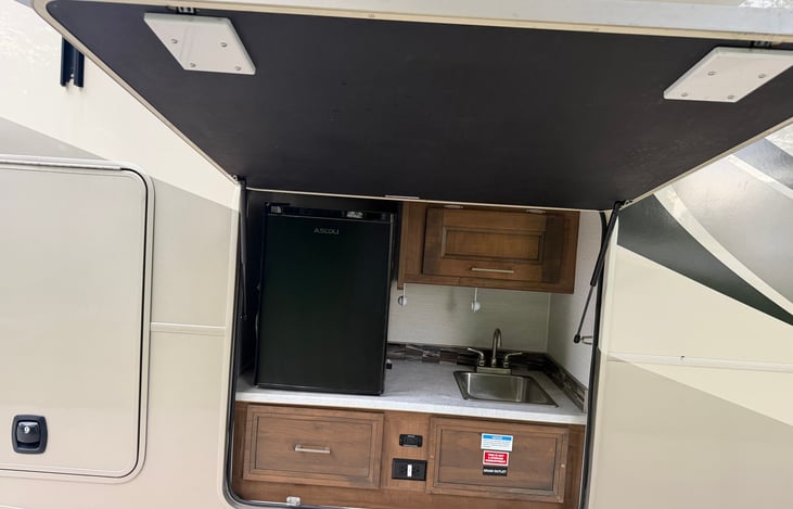 Outdoor Kitchen with refrigerator and sink.