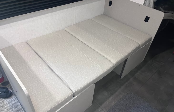 Table folded down to make 5th bed if needed.  Storage underneath each seat