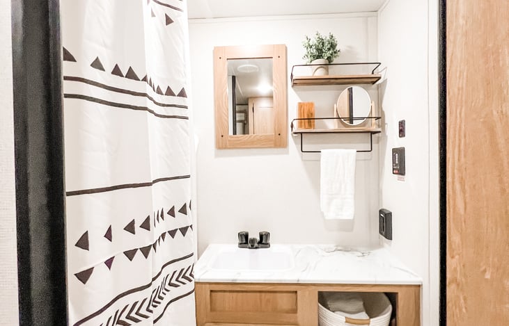 Bohemian themed bathroom with full sink, toilet and walk in shower.