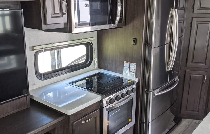 Kitchen with gas stove/oven microwave above. Full size refrigerator with ice maker. Island in the middle. Tons of cabinets and storage.