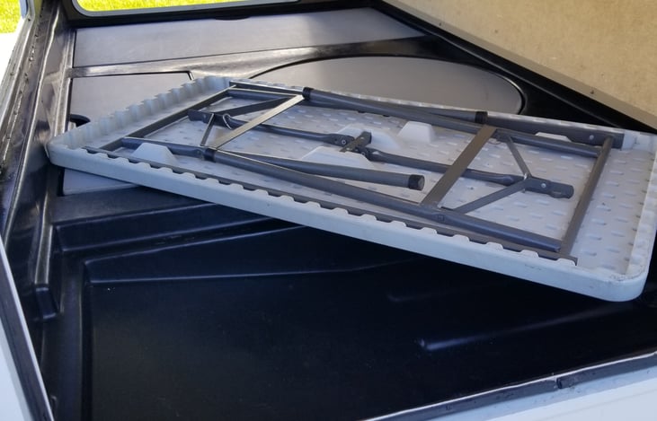Convenient storage for included folding table in rear compartment