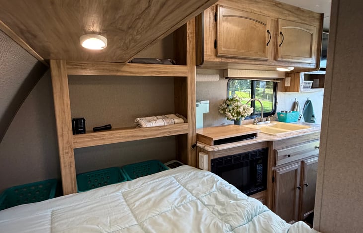 Convenient shelving and storage space near the bed for clothes, toiletries, makeup, and other personal items.