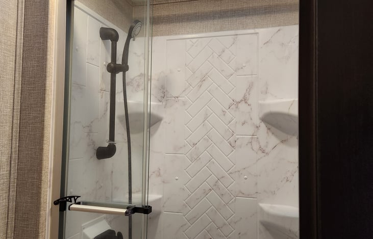 30x36 shower with adjustable showerhead, decorative surround, glass door, skylight, powered roof vent and ample lighting