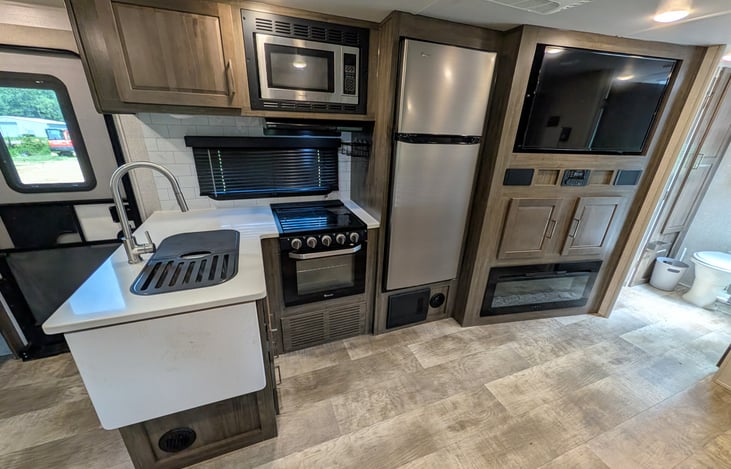 Spacious open-concept living area w/ dual recliners, TV & fireplace. Full kitchen features a residential fridge, 3-burner stove, oven, microwave, deep sink & booth dinette! Natural light throughout.