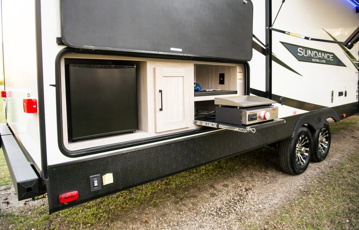 Convenient outdoor kitchen features a mini-fridge and slide-out propane griddle.