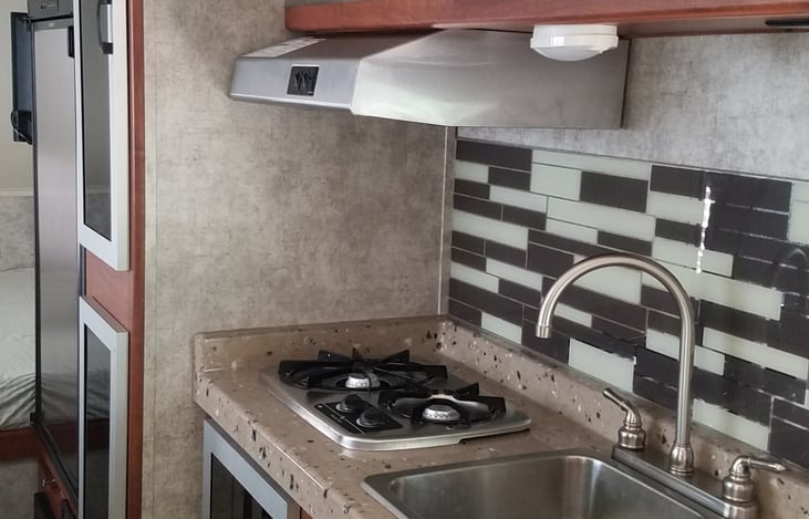2 burner gas stove top and oven, sink, microwave, plenty of food storage above and below the sink, small fridge and freezer.