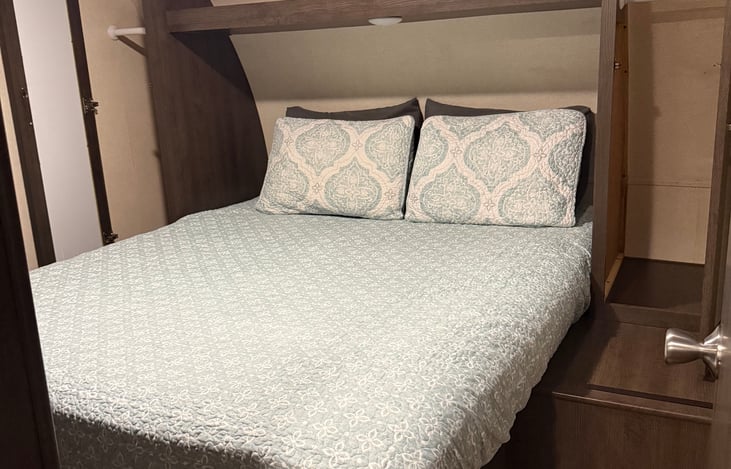 Master bedroom with queen bed and storage mirror on each side opened to show depth.