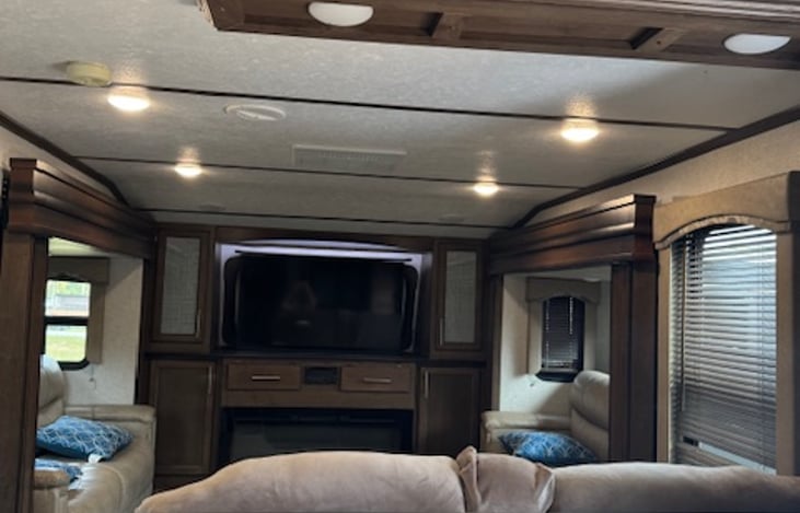 Front living room with SMART TV on elevator. Two couches that convert into double beds (one on each side) and set of recliners facing TV. Electric fireplace for ambiance and heat(if needed).