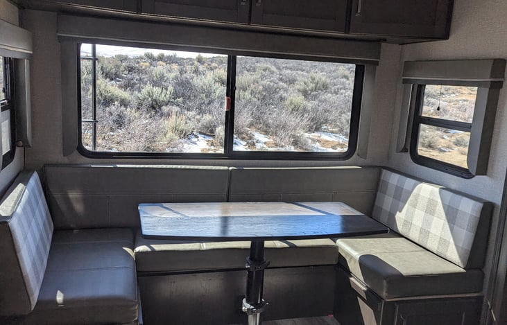 Large U shape dinette in rear of RV and large surround windows.