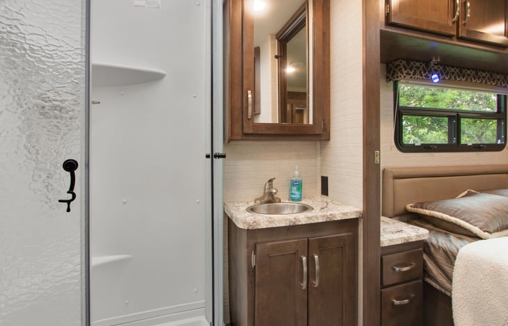 Bathroom sink and mirror and part of shower stall. very clean and spacious .