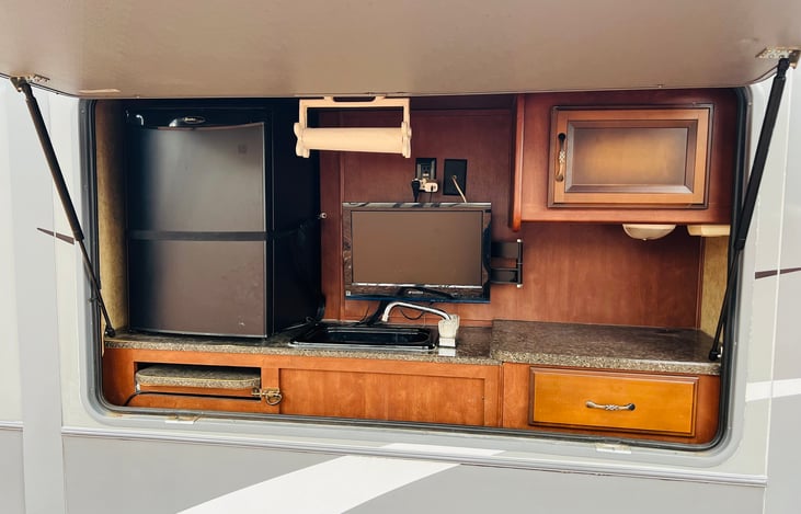 Outdoor kitchen with small fridge and sink.