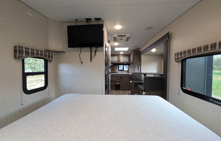 Cozy front bedroom featuring an upgraded residential mattress for a great night's sleep, TV, and bright windows with a massive automotive panoramic front view!