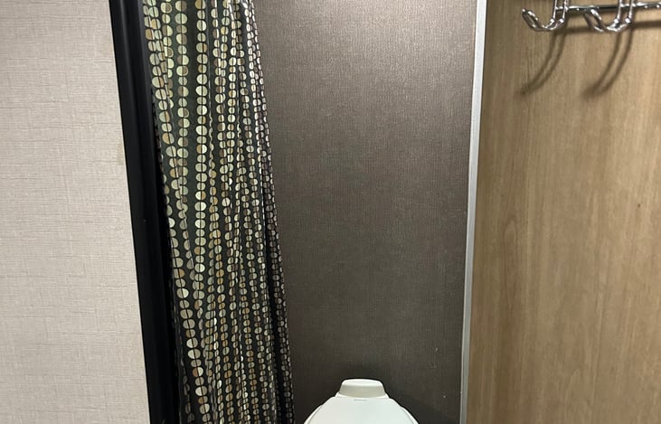 Bathroom with privacy door, toilet, and shower.