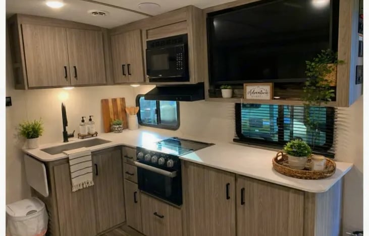The fully equipped kitchen makes cooking on the road simple and enjoyable. It includes a 3-burner cooktop with glass cover, oven, microwave, refrigerator, and a deep-bowl stainless steel sink.
