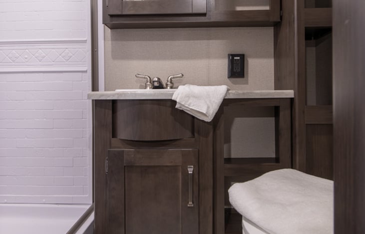 Bathroom sink, medicine cabinet and towel storage. Porcelain toilet under towel.