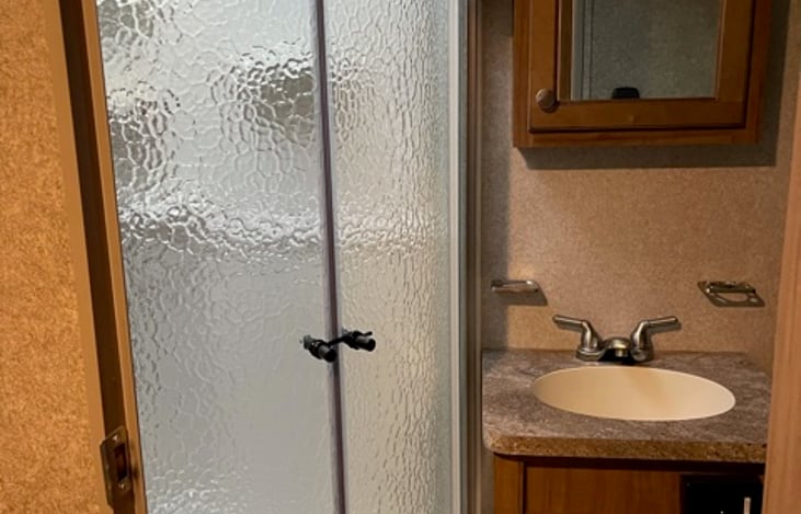 Bathroom with full shower, sink, toilet and vanity.