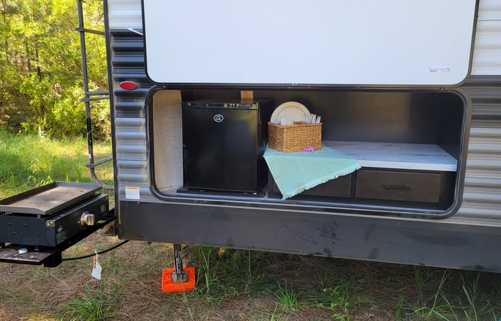 Outdoor kitchen including mini fridge (only works when hooked to power), two drawers, counter, and griddle.