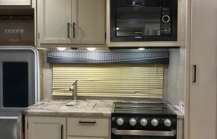 "Rolling Hills Retreat" has a 3-burner gas cooktop with glass cover, protective glass tile backing, and an overhead microwave.