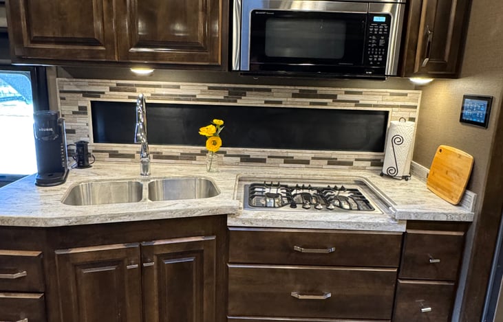 kitchen with double sink, 3-burner stove top, microwave/convection oven, Keurig, plenty of storage; galley window shade does open fully providing more light. Entrance door is to the left of counter