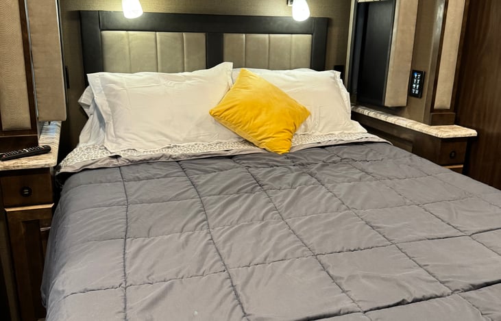 bedroom with queen bed. Panel controls on door side of room. Ceiling fan, Smart TV . Ambient lighting above the bed. Plenty of storage in bedroom.