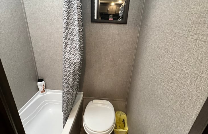 Bathroom has tub, shower, toilet, and mirror