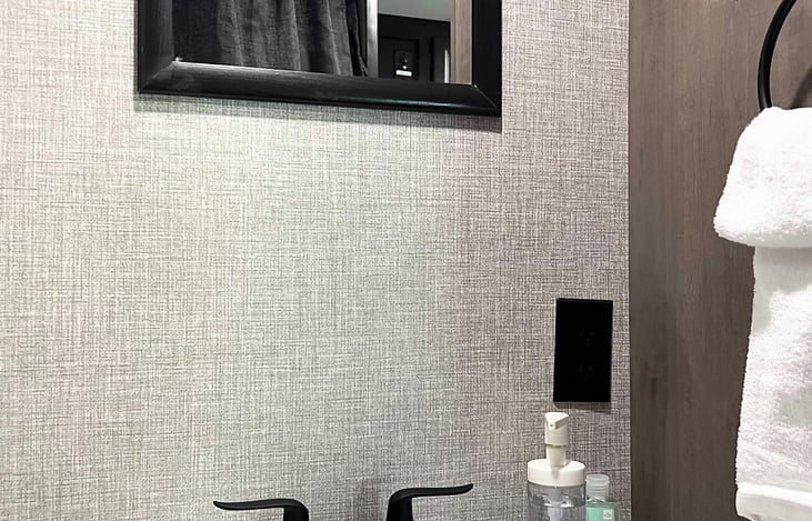 Bathroom sink with mirror, towel rack, and electrical outlet.