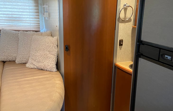 Full size bed adjacent to bathroom and sink.