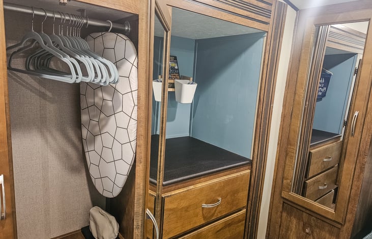 Hanging closet with velvet hangers, iron and ironing board
