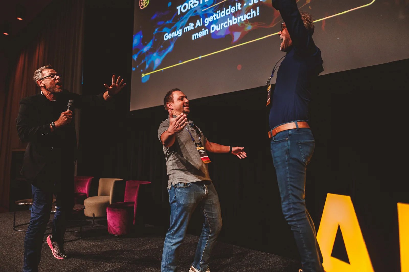 AITI Superevent Wien — Moment voller Freude auf der Bühne zwischen Mentor und Teilnehmern nach einem Durchbruch.
