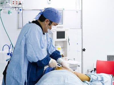 Médico realizando un tratamiento de lipoláser a un paciente recostado
