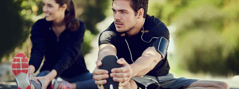 A man and a woman stretching their legs outdoors before exercising
