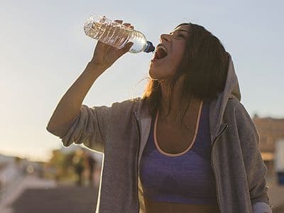 A woman drinking water from a bottle outdoors