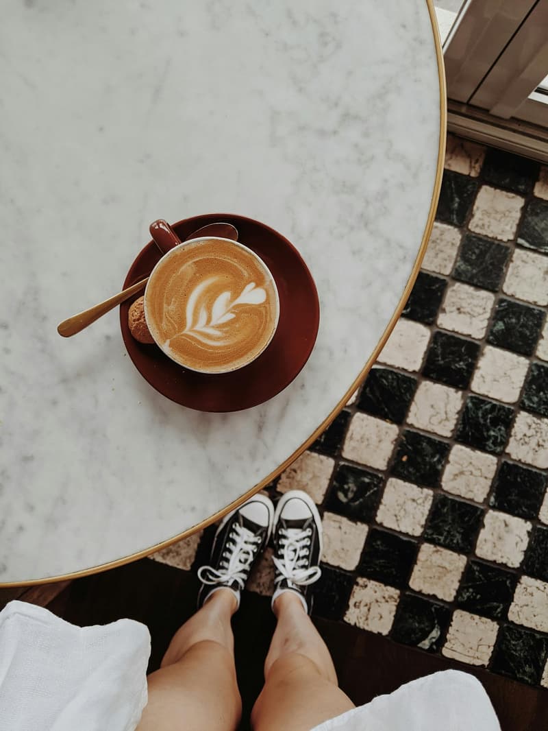 Vista superior de una mesa de mármol con una taza de café con arte latte