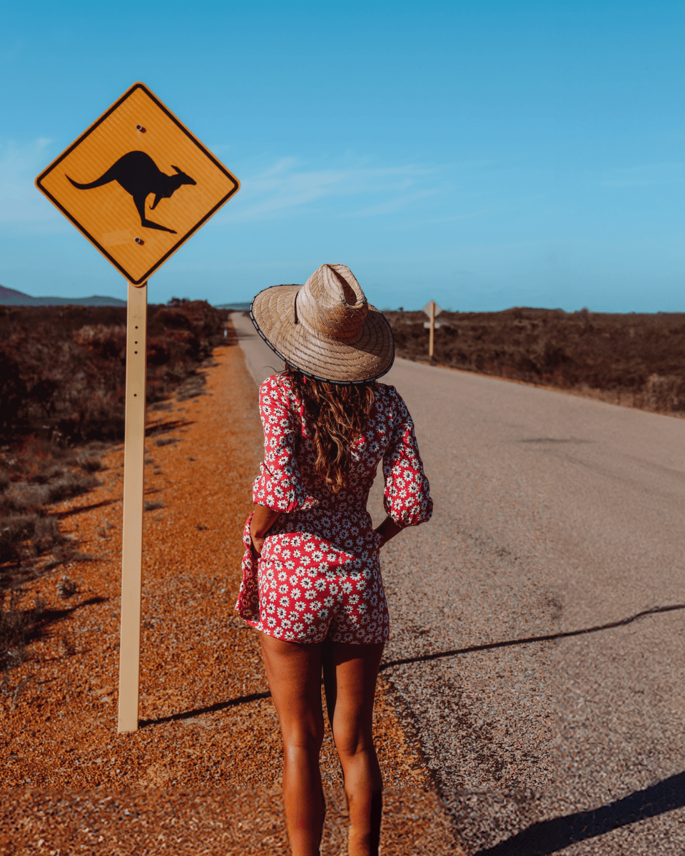 Mujer mirando una señal de transito con canguro en una carretera de Australia.